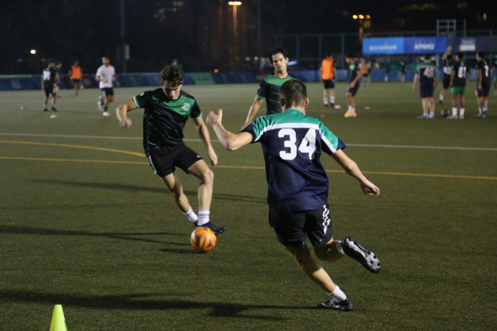 2 hommes jouant au football sur un terrain pendant la journée